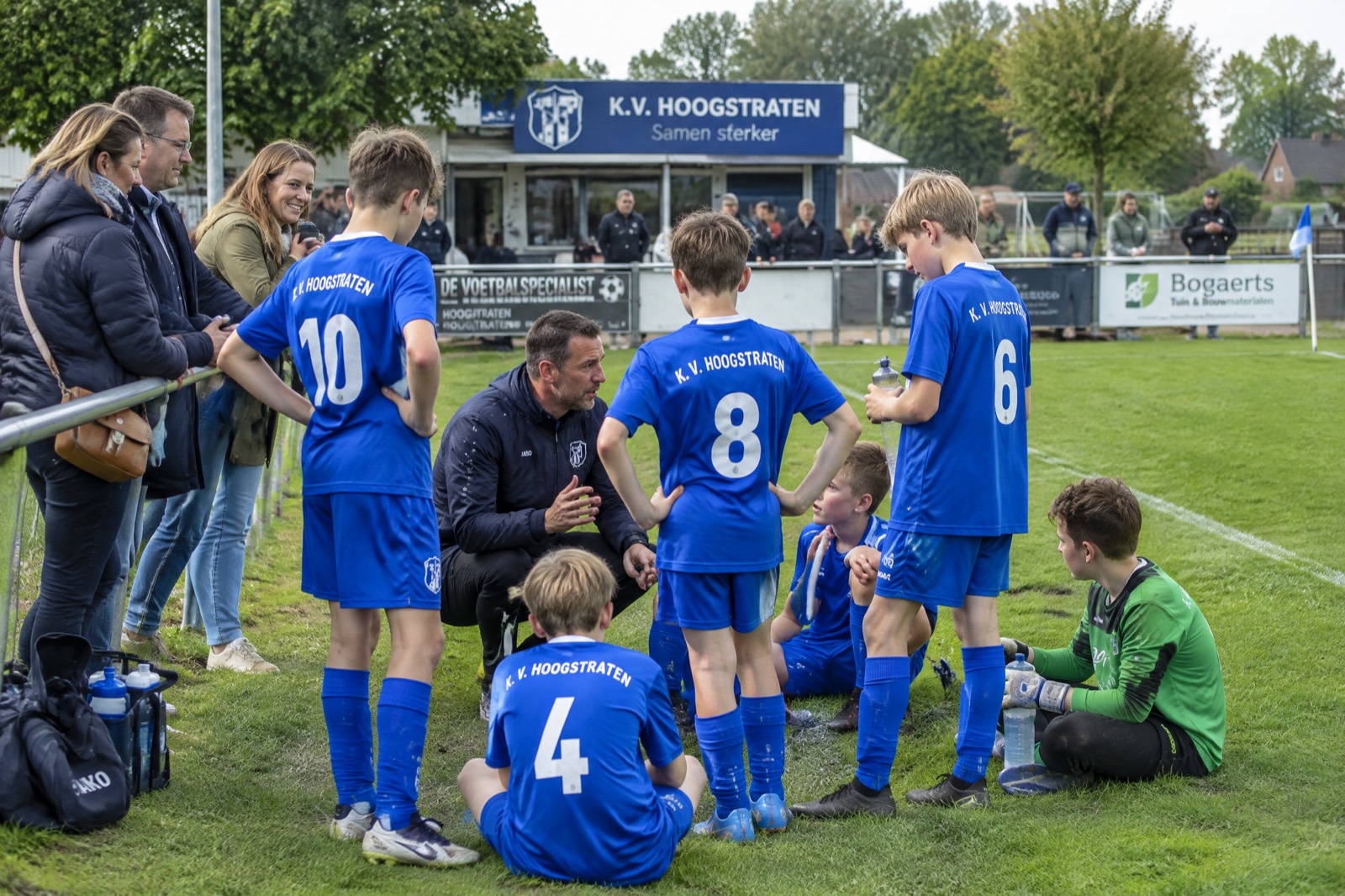 Een ploeg op het veld met trainer en ouders langs de lijn