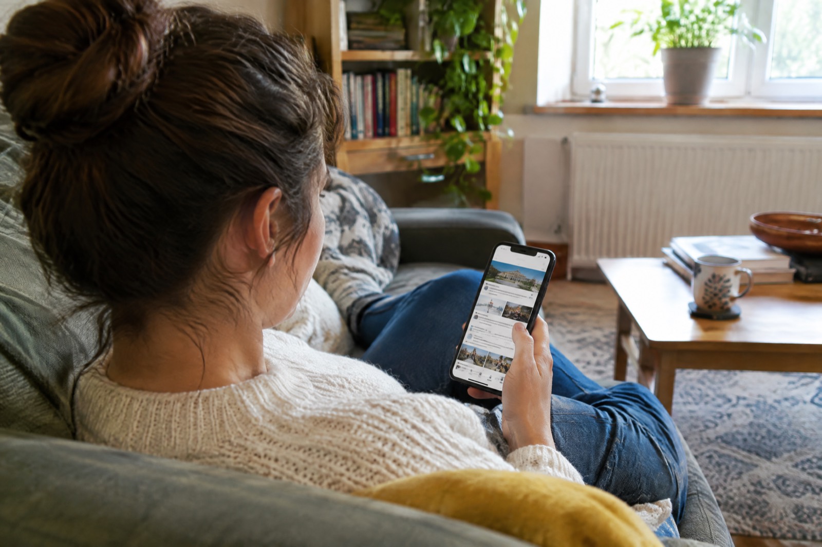 Iemand die in de zetel op een telefoon het nieuws van de vereniging leest
